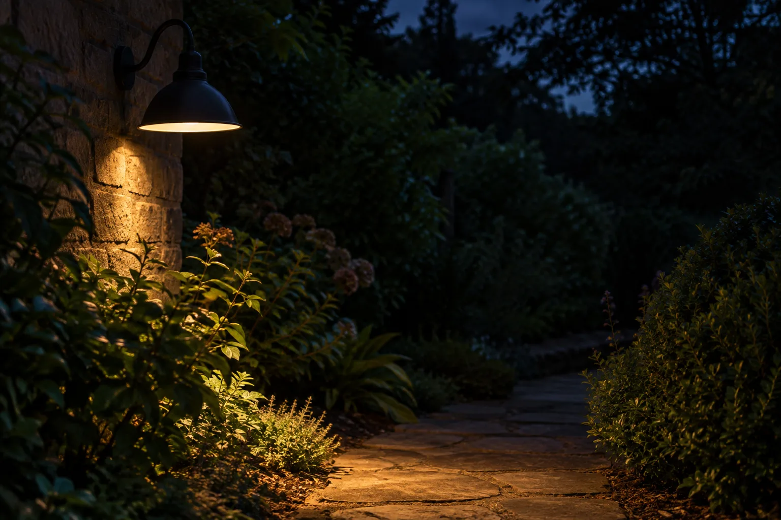Une lampe munie d’un abat-jour éclaire un chemin de jardin sans illuminer les arbustes autour.